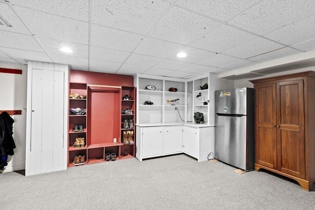 kitchen featuring light colored carpet, stainless steel fridge, and a drop ceiling