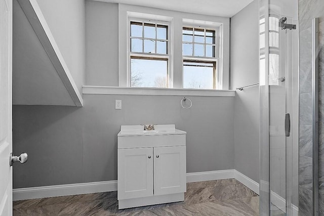 bathroom with marble look tile flooring, tiled shower, baseboards, and vanity