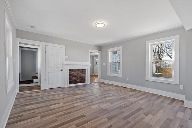 unfurnished living room with crown molding, wood finished floors, and baseboards
