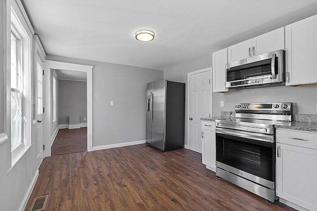 kitchen featuring appliances with stainless steel finishes, baseboards, dark wood-style floors, white cabinets, and light stone counters
