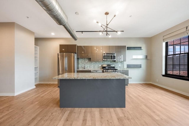 kitchen featuring light wood-type flooring, gray cabinets, light stone counters, and stainless steel appliances