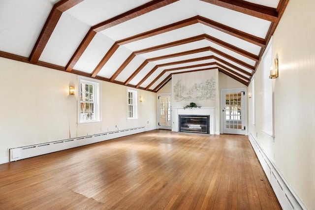 unfurnished living room featuring a baseboard heating unit, a healthy amount of sunlight, and hardwood / wood-style flooring