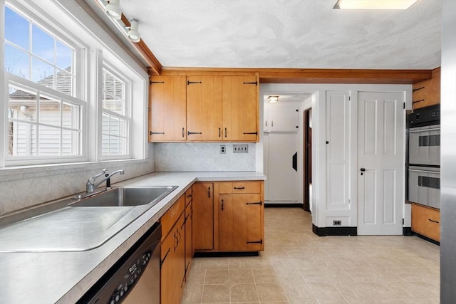 kitchen with a sink, light countertops, appliances with stainless steel finishes, tasteful backsplash, and brown cabinets