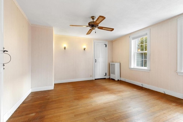 spare room with crown molding, baseboards, radiator heating unit, hardwood / wood-style flooring, and a ceiling fan