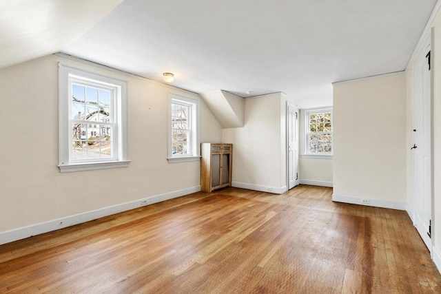 additional living space featuring lofted ceiling, baseboards, and light wood finished floors