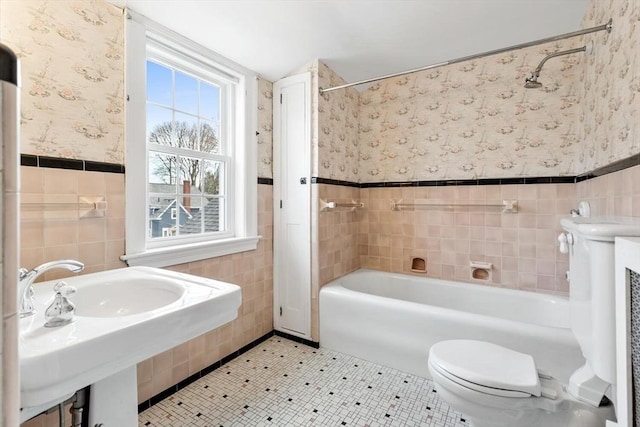 bathroom featuring tile patterned flooring, wallpapered walls, a wainscoted wall, toilet, and tile walls