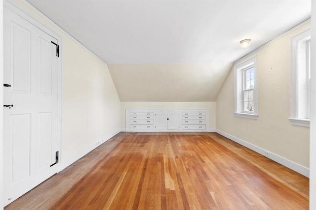 bonus room with light wood-type flooring, baseboards, and vaulted ceiling