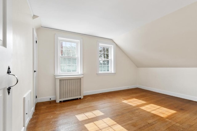 bonus room with baseboards, wood-type flooring, radiator, and vaulted ceiling