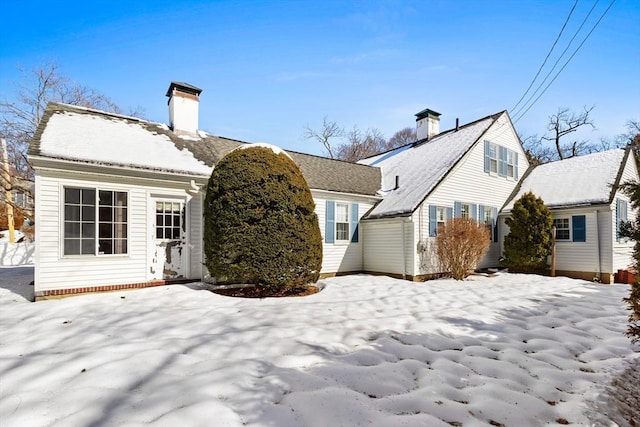 snow covered back of property featuring a chimney