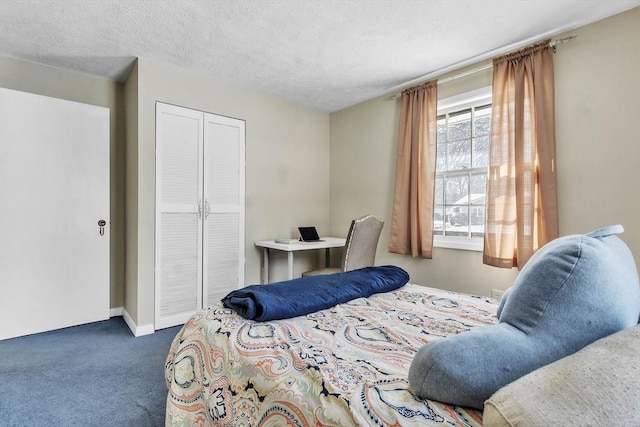 bedroom featuring a textured ceiling, dark carpet, and a closet