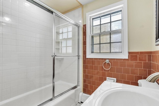 bathroom with enclosed tub / shower combo, sink, and tile walls