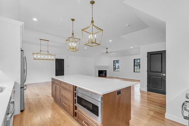 kitchen featuring a kitchen island, recessed lighting, a fireplace, light wood-style floors, and appliances with stainless steel finishes