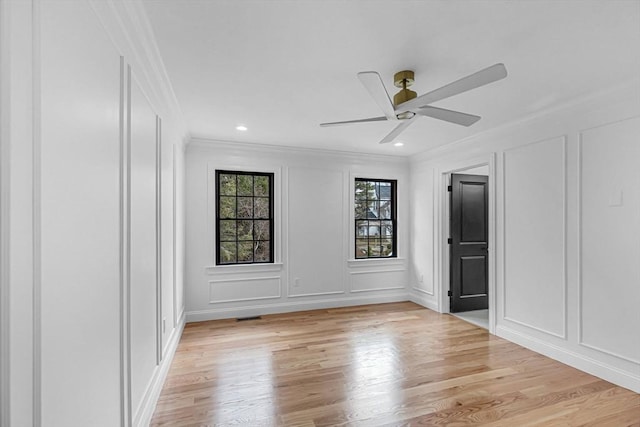 unfurnished bedroom featuring recessed lighting, light wood-style flooring, ornamental molding, and a decorative wall