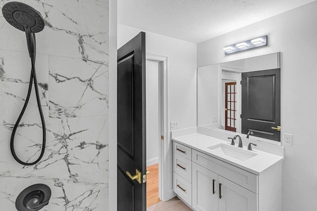 full bath with a marble finish shower and vanity