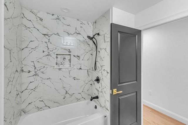 bathroom featuring bathtub / shower combination, wood finished floors, and baseboards