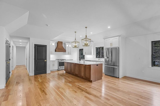 kitchen with a kitchen island, light countertops, appliances with stainless steel finishes, custom exhaust hood, and white cabinets