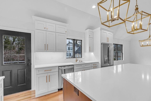 kitchen with light wood finished floors, a sink, light countertops, white cabinets, and appliances with stainless steel finishes