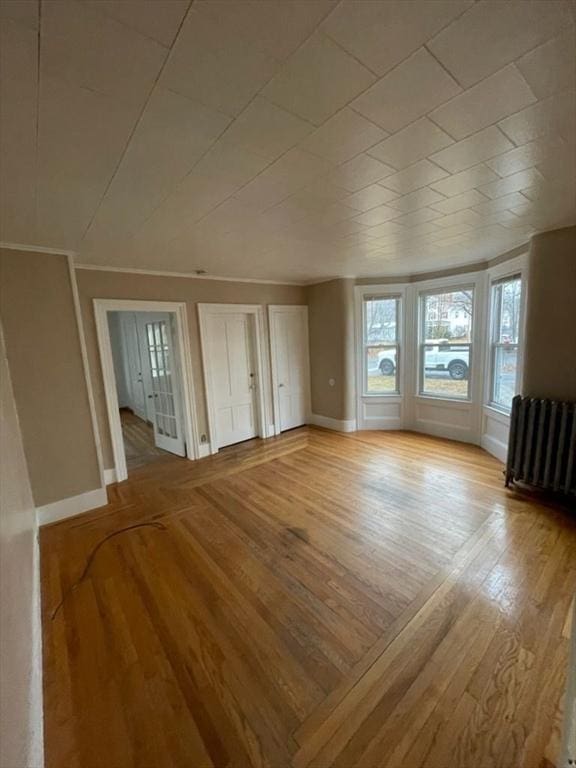 unfurnished living room with radiator, crown molding, and light hardwood / wood-style flooring