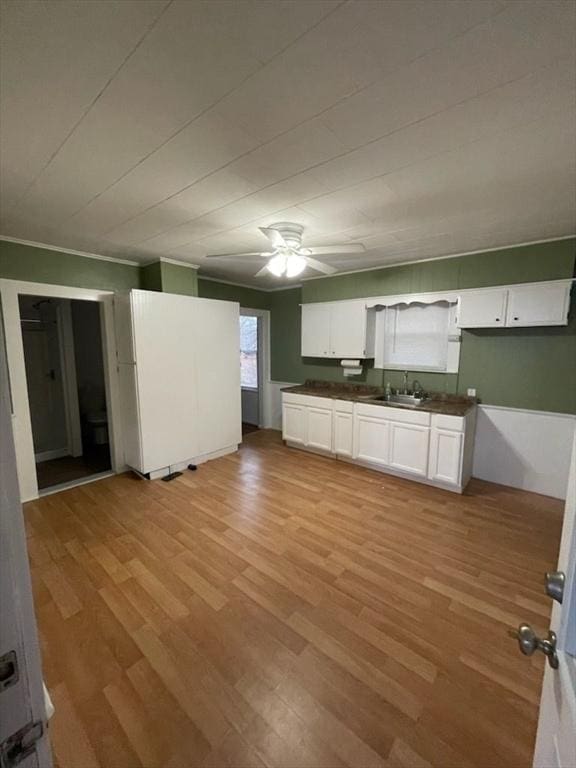 kitchen with light wood-type flooring, white cabinetry, and sink