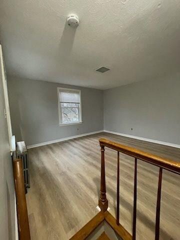 additional living space with wood-type flooring and a textured ceiling