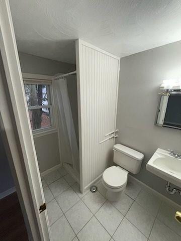 bathroom with tile patterned floors, curtained shower, toilet, and sink