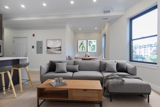 living room featuring electric panel, visible vents, ornamental molding, light wood-style floors, and recessed lighting