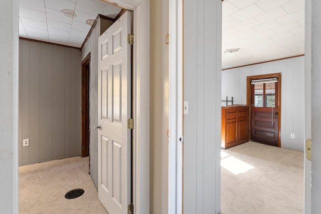 hallway with light colored carpet and wooden walls