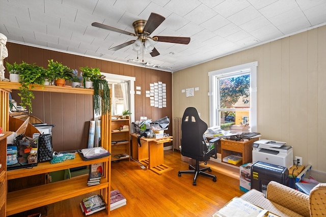 office area with wood-type flooring, ceiling fan, and wood walls