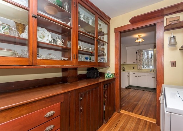 bar with dark wood-type flooring, range, and a sink