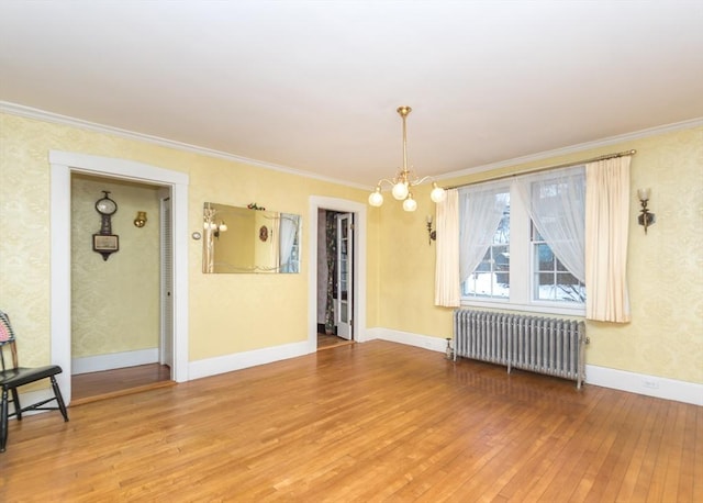 spare room with light wood finished floors, baseboards, ornamental molding, radiator, and an inviting chandelier