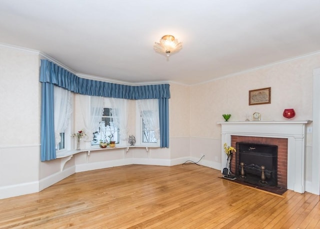 unfurnished living room with wood-type flooring, a brick fireplace, ornamental molding, and baseboards