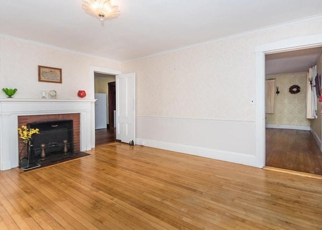 unfurnished living room with baseboards, a fireplace, ornamental molding, and hardwood / wood-style flooring