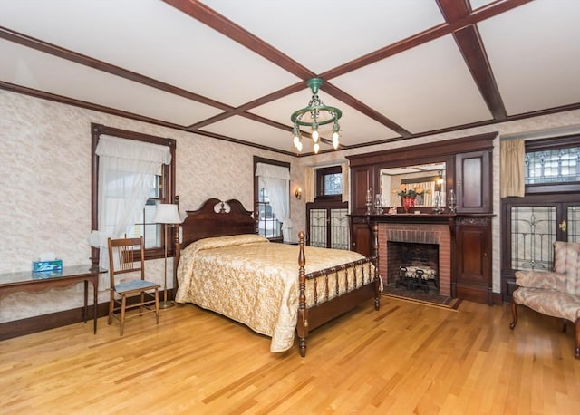 bedroom with light wood finished floors, a fireplace, and crown molding