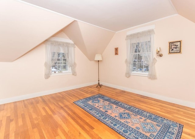 additional living space with baseboards, vaulted ceiling, and wood finished floors
