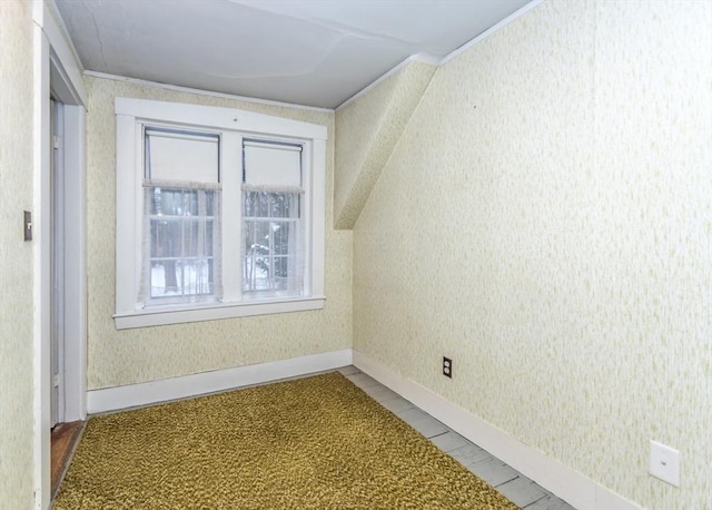 bonus room with baseboards and wallpapered walls
