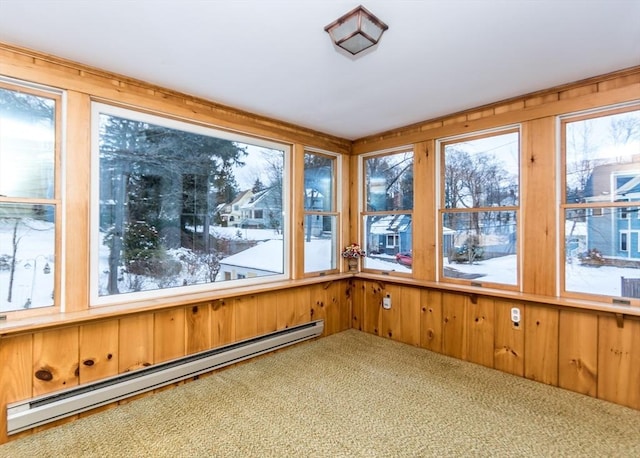 unfurnished sunroom featuring wood walls, a baseboard heating unit, and carpet flooring