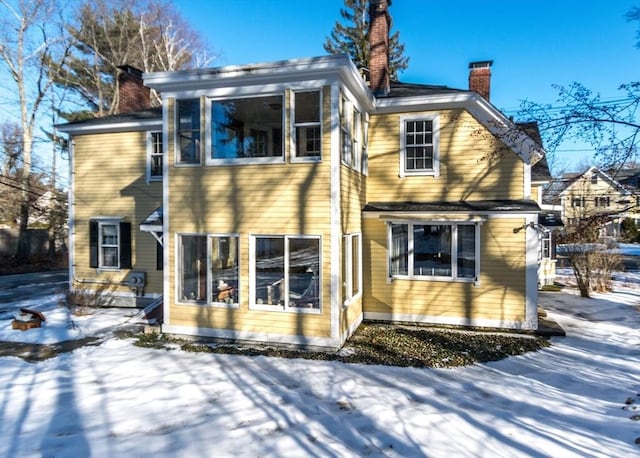 snow covered house featuring a chimney
