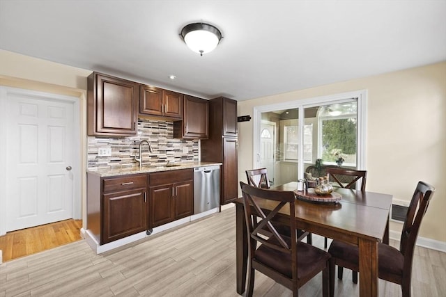 kitchen with tasteful backsplash, stainless steel dishwasher, dark brown cabinetry, sink, and light hardwood / wood-style flooring