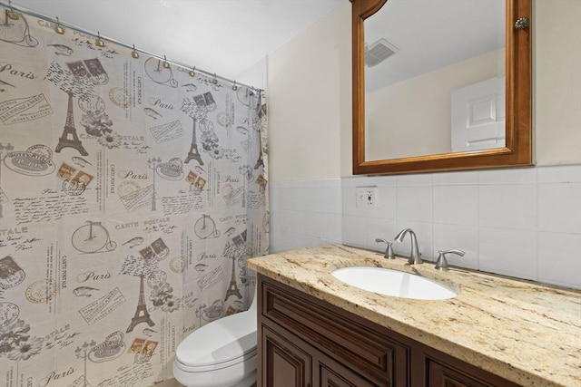 bathroom with vanity, toilet, tile walls, and walk in shower