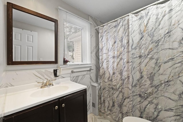 bathroom with curtained shower, vanity, tile walls, and toilet