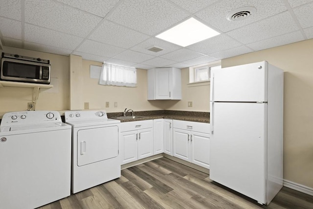 clothes washing area with hardwood / wood-style flooring, sink, and washing machine and clothes dryer