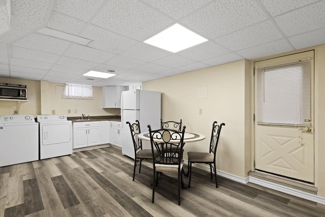 kitchen with white cabinetry, a drop ceiling, dark hardwood / wood-style flooring, white refrigerator, and washer and clothes dryer