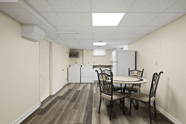 dining area with dark hardwood / wood-style flooring, a drop ceiling, heating unit, sink, and separate washer and dryer