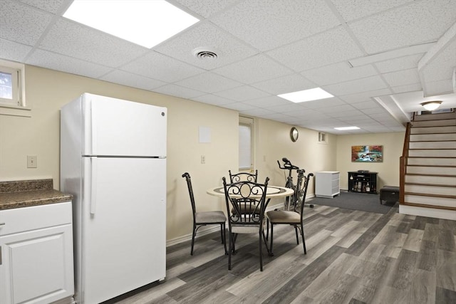 dining space with a paneled ceiling and dark hardwood / wood-style flooring