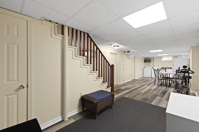 interior space with a paneled ceiling, white refrigerator, washer / dryer, and hardwood / wood-style flooring