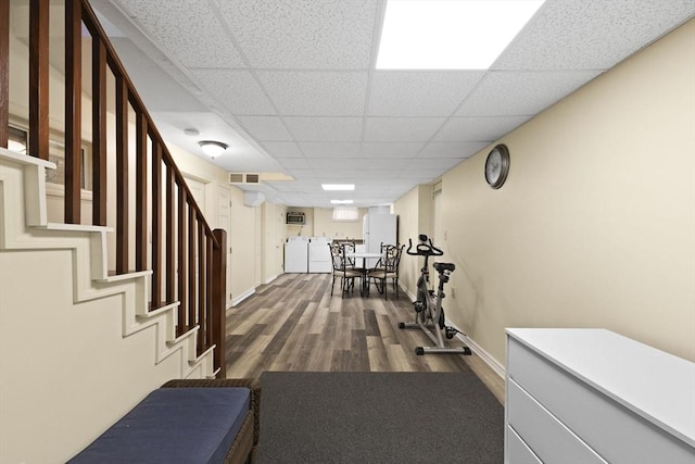 workout area featuring a paneled ceiling and wood-type flooring