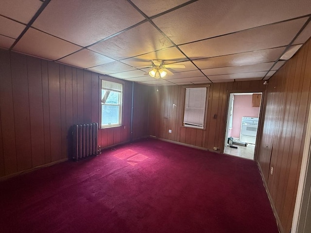 64 Suffolk St, Worcester, MA 01604 - empty room with radiator heating unit, carpet floors, ceiling fan, and wood walls