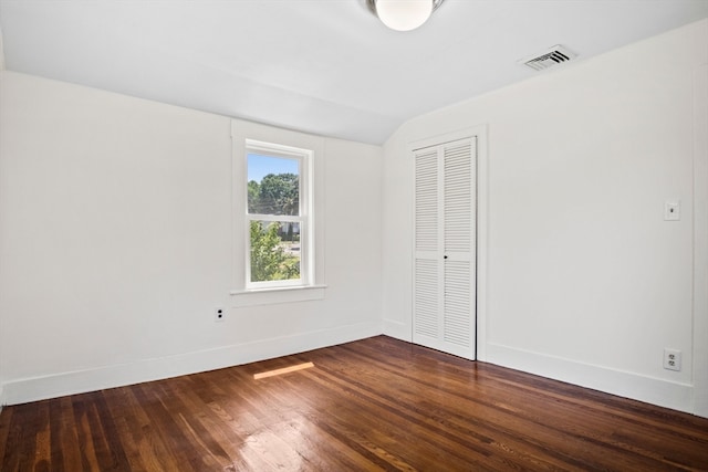 spare room featuring vaulted ceiling and dark wood-type flooring