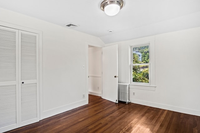 unfurnished bedroom with a closet, dark wood-type flooring, and radiator heating unit