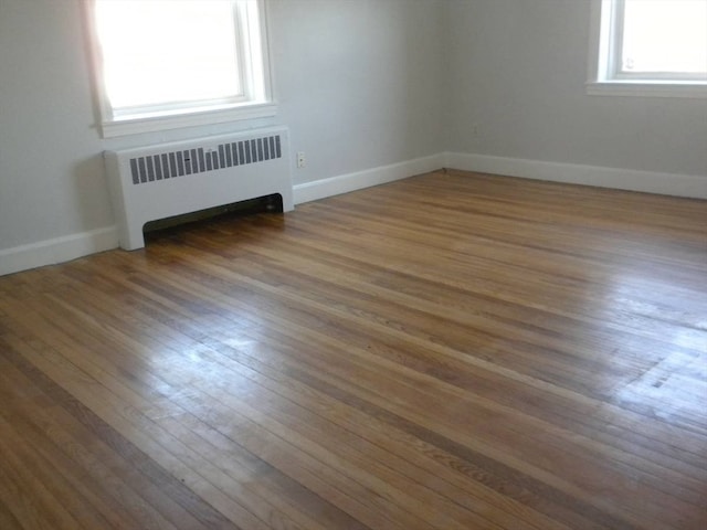 empty room with dark hardwood / wood-style flooring, radiator heating unit, and a wealth of natural light